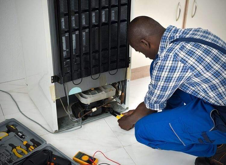 Technician performing fridge repairs in Johannesburg